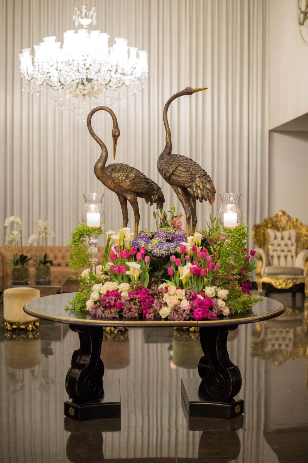 עיצוב שולחן עם פסלי חסידות ופרחים צבעוניים באולם אירועים יוקרתי, מתאים לאירועים מיוחדים.