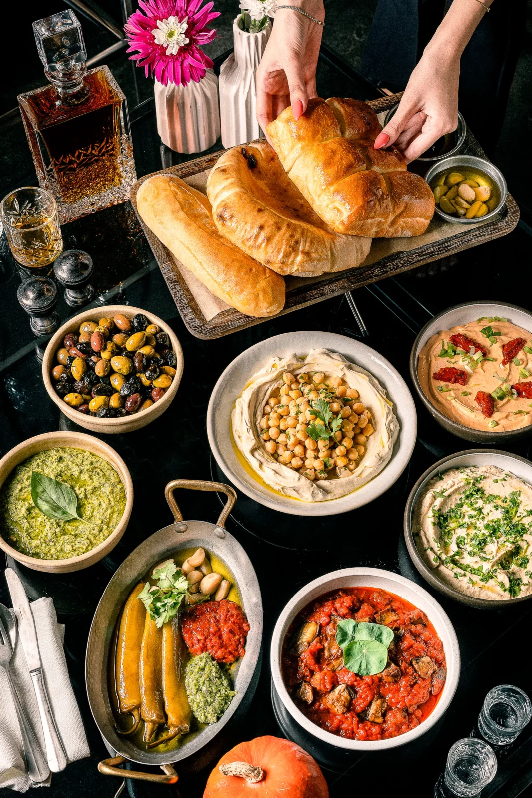 מגוון מנות טעימות עם לחמים, סלטים ורוטבים על שולחן, מושלם לאירועים קטנים ואירועי בוטיק.