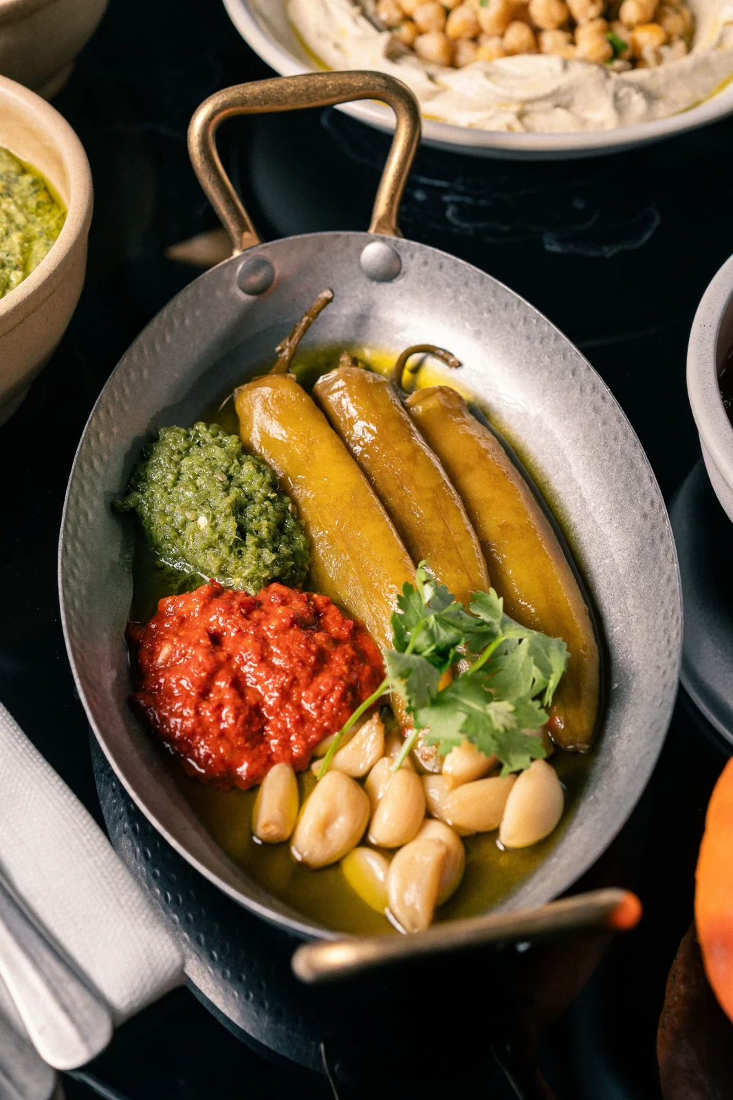 צלחת עם פפריקות, רטבים ירוקים ואדומים, ושיניים קלופות, מוגשת באולם אירועים יוקרתי.