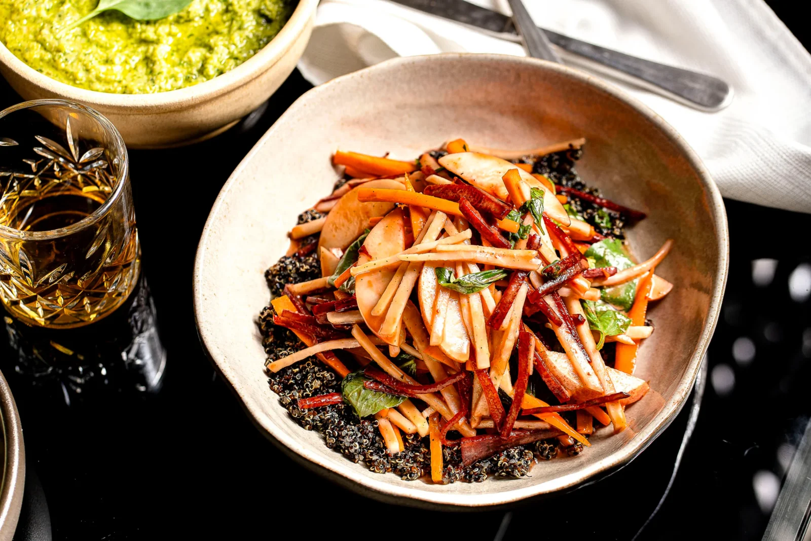 סלט צבעוני עם ירקות קצוצים, קינואה ורטבים, מוגש עם כוסית משקה.