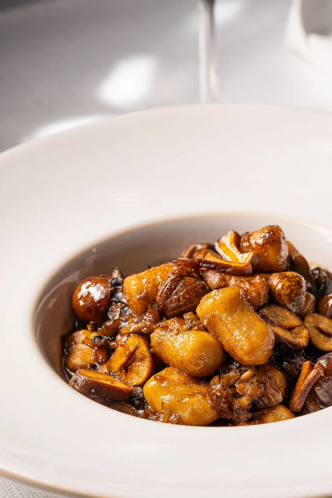 צלחת עם מנת פסטה מעוצבת, מוקפצת עם פטריות ובצל, בסגנון גורמה.