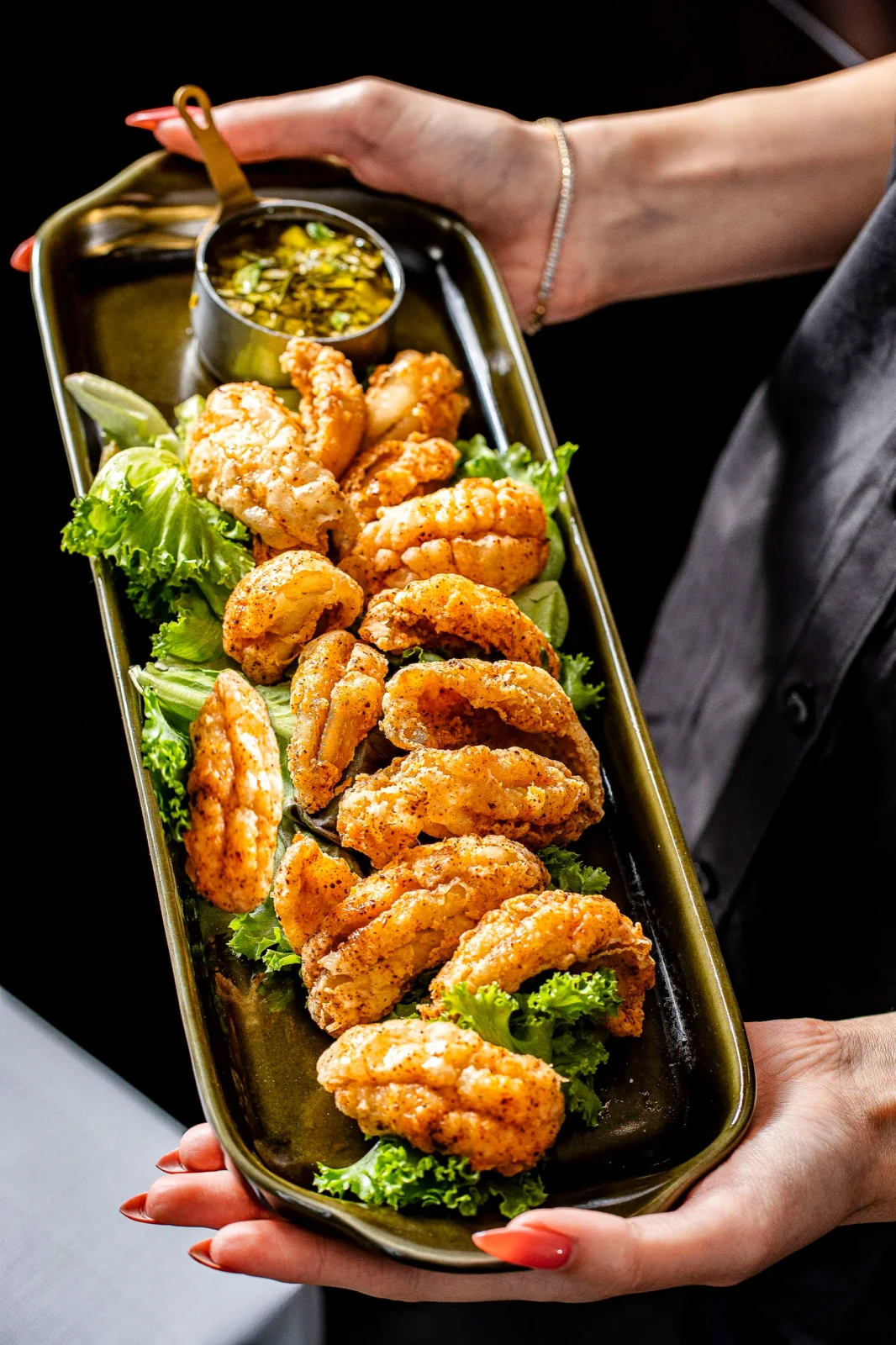 צלחת עם פירות ים מטוגנים מונחים על עלי חסה, עם רוטב בצד. מתאים לאירועים יוקרתיים.