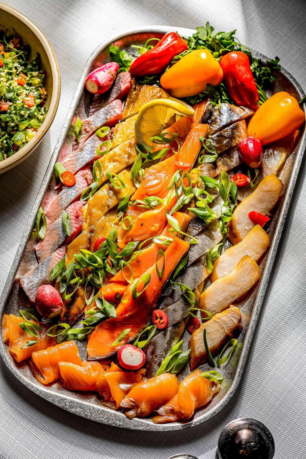 platter עם מגוון דגים מעושנים, ירקות קצוצים ורוטב, מתאים לאירועים קטנים ואולמות אירועים יוקרתיים.