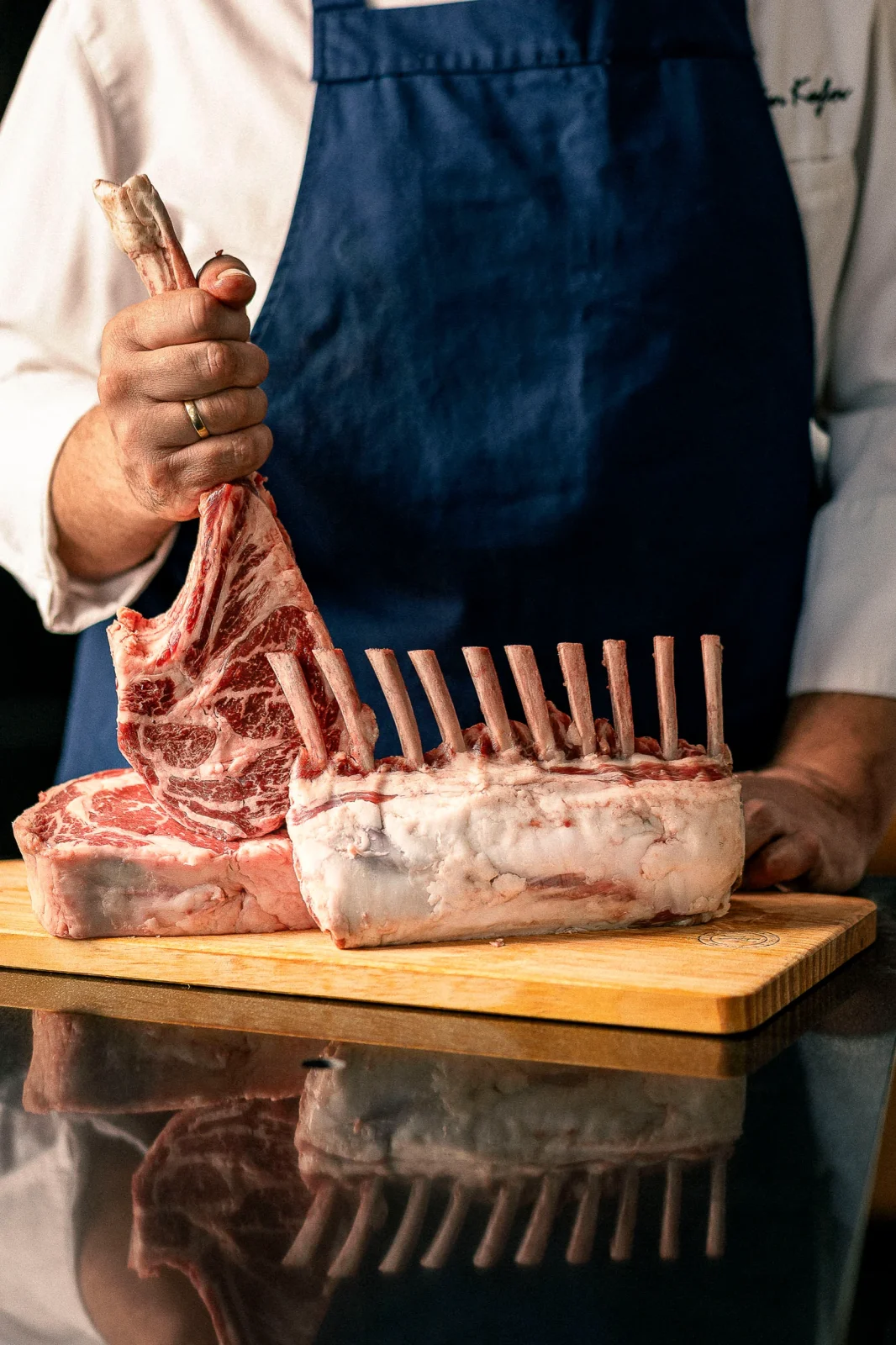 שף מחזיק בנתח בשר מפואר על גבי קרש חיתוך, מוכן לבישול או צלייה.